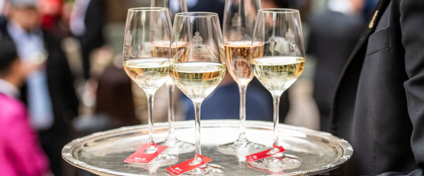 Five glasses of champagne stand on a silver serving tray
